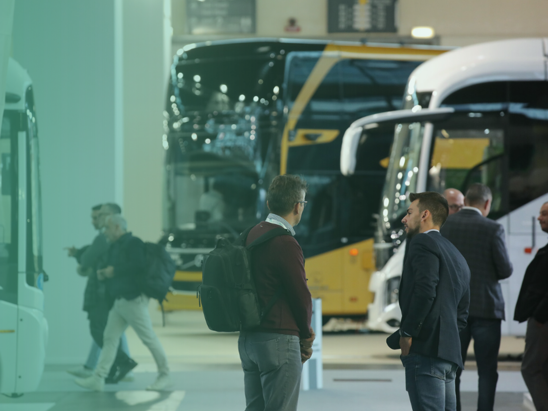 Persone che parlano davanti a bus esposti in fiera.